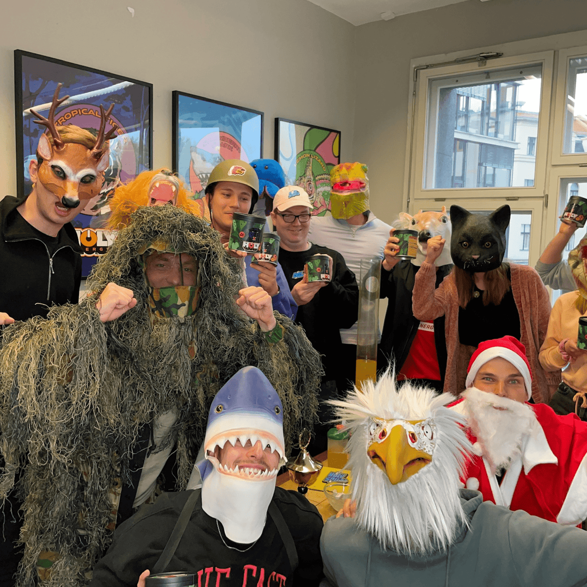 Gruppe von Menschen in Tier- und Weihnachtsmasken, die Pappdosen in die Kamera halten.
