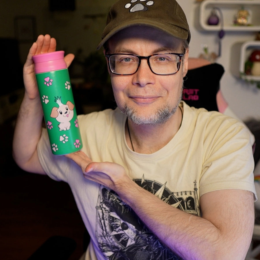 Ein Mann mit Brille und Mütze hält einen grünen Shaker mit einem Cartoon-Hund darauf.